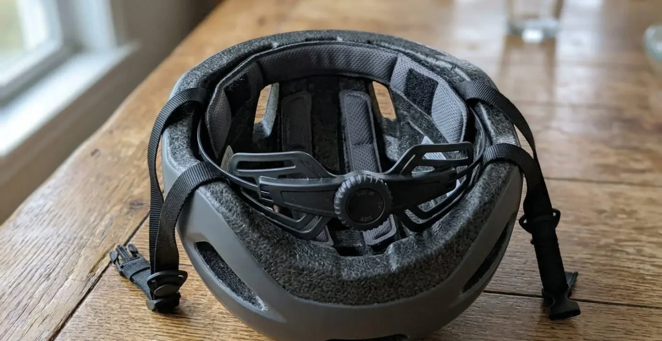 Gros plan sur l'intérieur d'un casque vélo montrant la mousse et le système de réglage, posé sur une table en bois